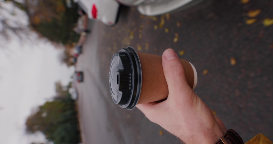 POV man carry paper coffee cup walking on the city road at the autumn day, vertical video Royalty-Free Stock Footage #1097215601