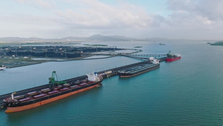 Aerial high angle drone footage of bulk carrier cargo ships docked at Gladstone coal terminal in Central Queensland, Australia. Gladstone operates one of Australia