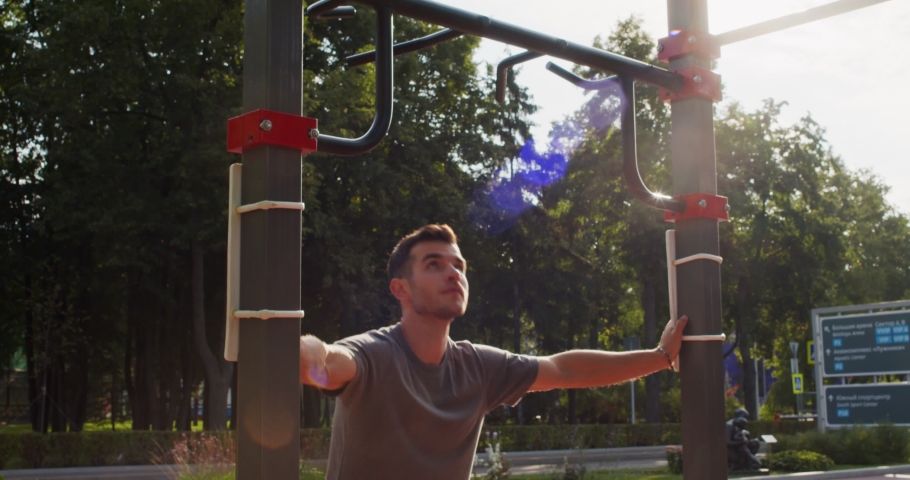 Athletic young man doing pull up exercise on horizontal bars during intense fitness workout in daytime outdoors Royalty-Free Stock Footage #1097218231