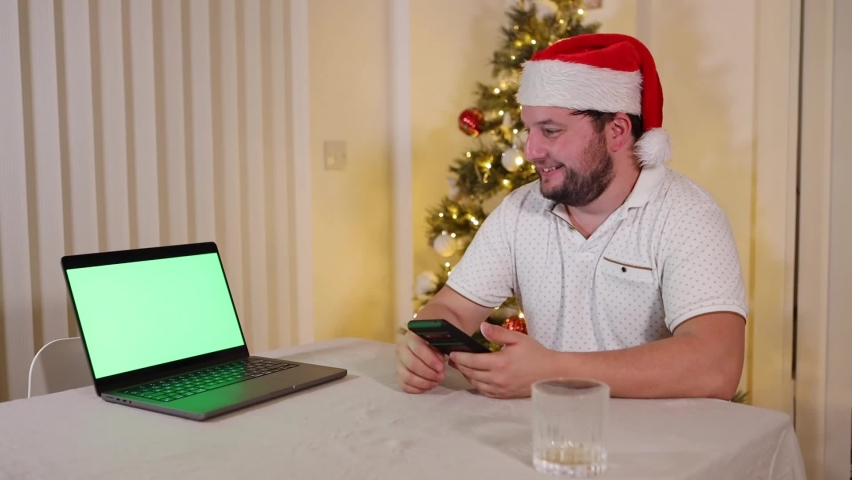 Bearded festive man watching something amusing on green screen laptop computer holding smartphone then focusing on the laptop video | Shutterstock HD Video #1097220363