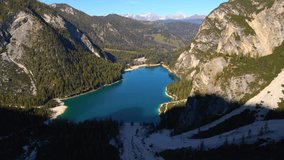 Footage at Lago di Braies, up the mountains in European Alps in Italian Dolomites. Video of a glaciar lake, mountains, filmed from above with a drone flying with smooth movement in 4k