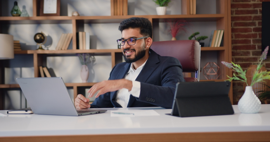 Good-looking indian businessman customer talking, having virtual meeting working on laptop computer giving online training, remote class on video conference call at modern office Royalty-Free Stock Footage #1097223327