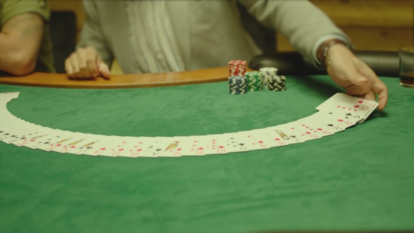 Casino: Dealer man shuffles the playing cards and performing trick with cards on green colored table. Concept of poker , black jack . Shot on ARRI ALEXA Cinema Camera in slow motion , close up .  | Shutterstock HD Video #1097224483