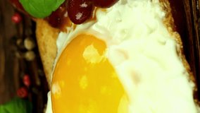 Cooking of sandwich or bruschetta with red beans and fried egg on toasted bread. Decorate with basil leaf. Delicious English breakfast in home kitchen.