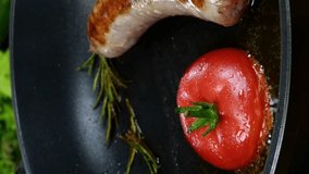 Bavarian sausages with tomato and sprig of rosemary are fried in frying pan and fried eggs with flowing yolk. English or German, European or American breakfast.