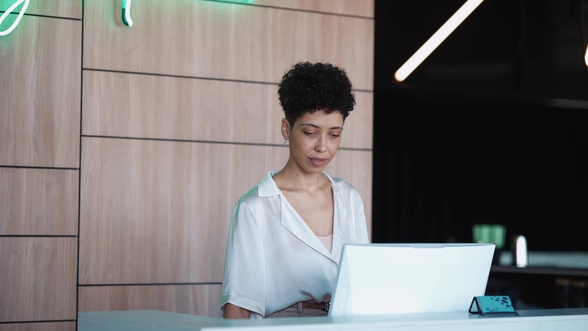 A confident woman receptionist stands at the front desk of the hotel Royalty-Free Stock Footage #1097230591