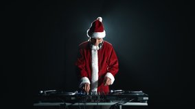 Happy Christmas DJ in Santa Claus costume playing music and dancing on party in night club
