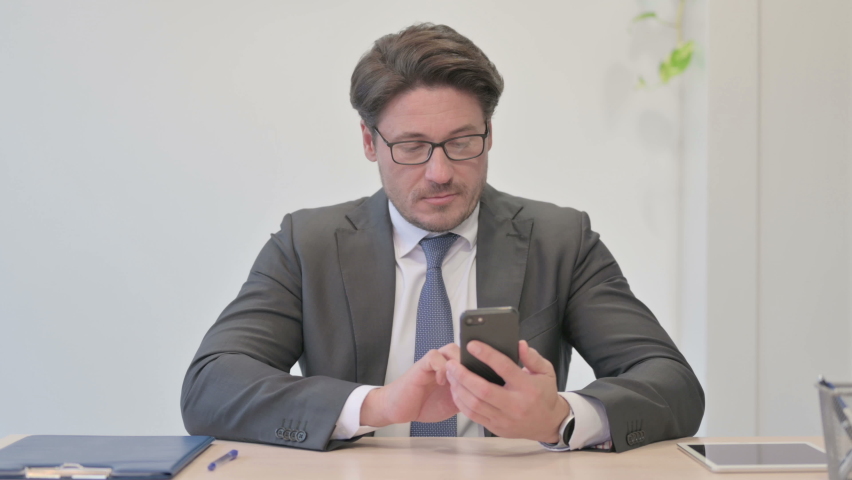 Middle Aged Businessman Celebrating Online Success on Smartphone in Office | Shutterstock HD Video #1097231777