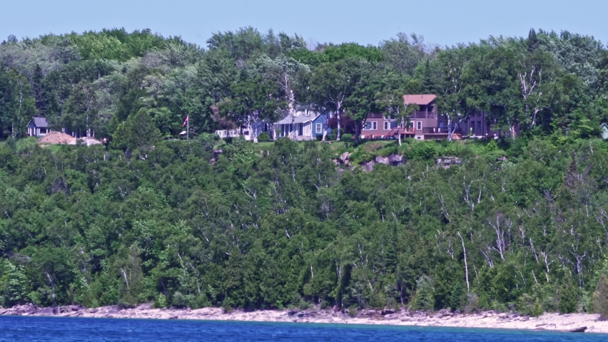 Cottages at limestone rocky cliff with green forest by Lake Huron Lion