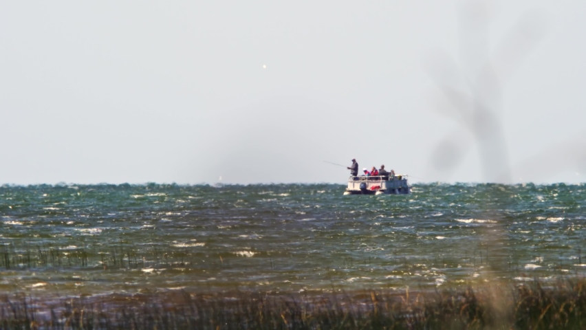 Long distance and very hot summer air make jelly effect at lake water and fishermen on the boat. Cottage life on the lake depiction, relaxing tranquil fishing on a boat at peaceful summer. Background