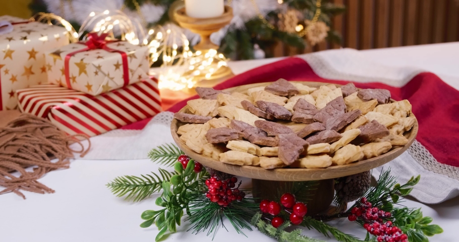 Decorating the table with homemade cookies and Christmas gifts. A woman's hand lays cookies on a wooden plate, decorating the festive table. High quality 4k footage | Shutterstock HD Video #1097235463