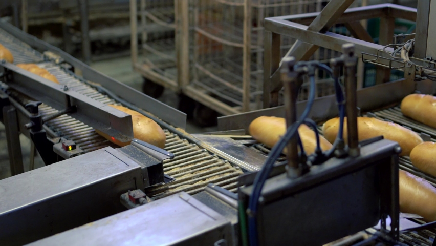 A production line in the bread-making factory on an automated conveyor belt. Close up on bread being prepared in the production factory. Food manufacturing concept. | Shutterstock HD Video #1097235491