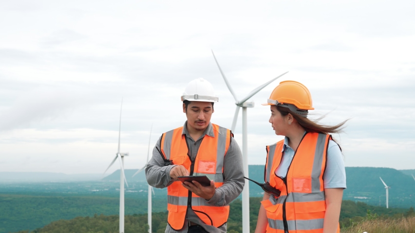 Male and female engineers working on a wind farm atop a hill or mountain in the rural. Progressive ideal for the future production of renewable, sustainable energy. | Shutterstock HD Video #1097240915