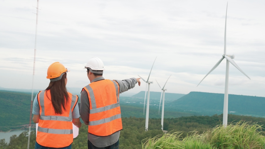 Male and female engineers working on a wind farm atop a hill or mountain in the rural. Progressive ideal for the future production of renewable, sustainable energy. | Shutterstock HD Video #1097240961