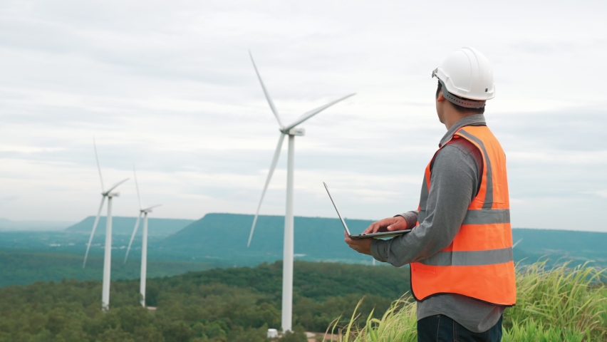 Engineer working on a wind farm atop a hill or mountain in the rural. Progressive ideal for the future production of renewable, sustainable energy. Energy generation from wind turbine. | Shutterstock HD Video #1097240979