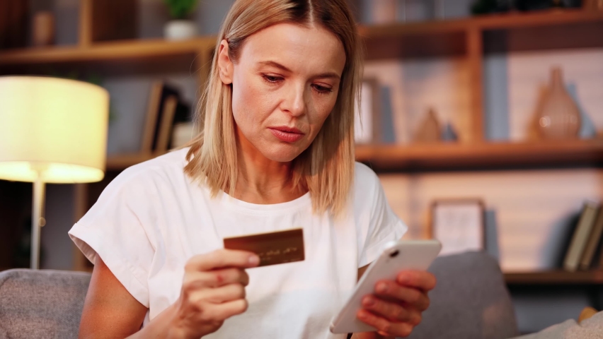Portrait of charming middle aged woman browse products in internet store on smartphone while finds promotional sale offer and immediately reached for credit card starting to make purchase online
 | Shutterstock HD Video #1097242075