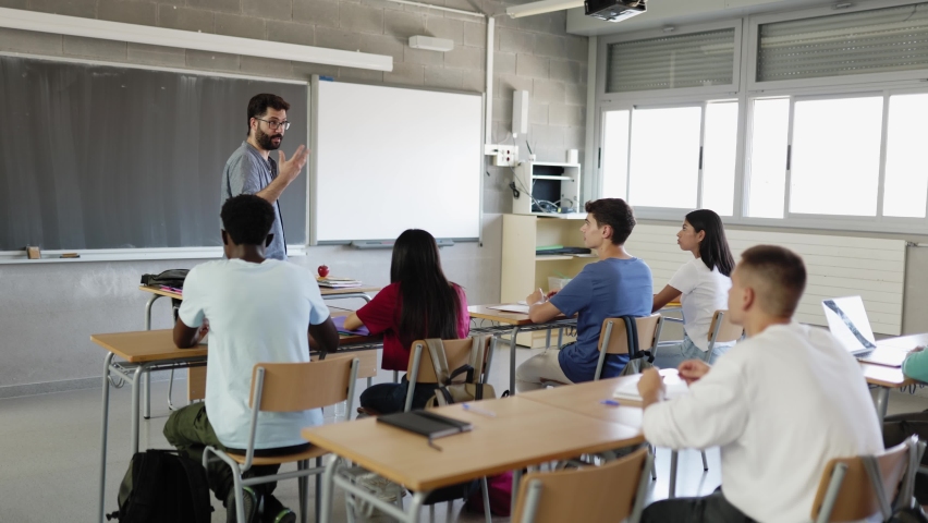 Young male teacher explaining lesson to multiracial group of teenage students at school. Education concept | Shutterstock HD Video #1097242107