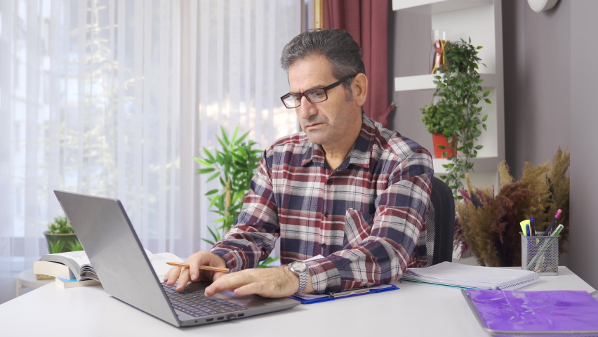 Man working in home office studies taking notes.
Man in glasses working from his laptop at home office and making notes on paper.
 | Shutterstock HD Video #1097243015