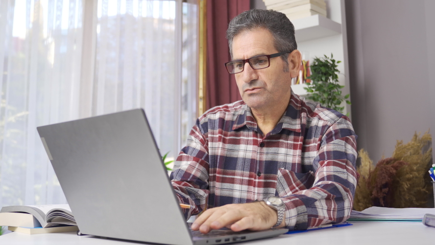 Businessman in glasses working in home office looking at laptop.
Man in glasses working from his laptop at home office and making notes on paper.
 | Shutterstock HD Video #1097243027