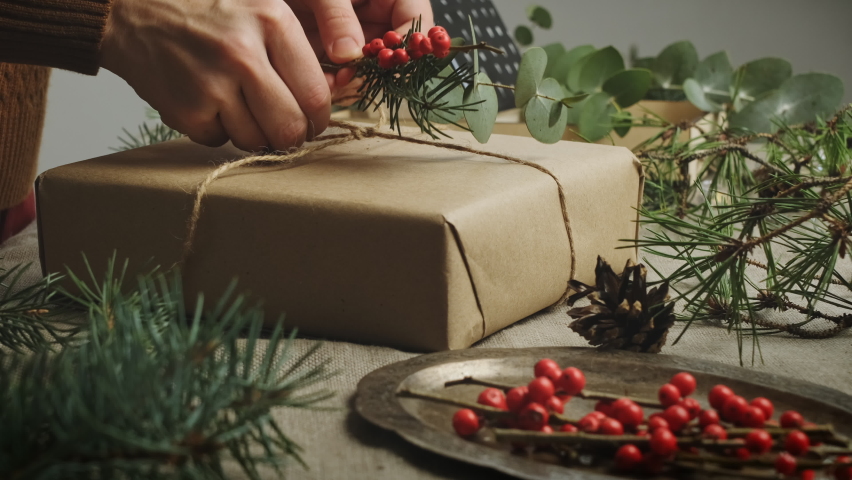 Boxing day, sustainable Christmas gift wrapping. Woman hands decorating Christmas present with fresh twigs. | Shutterstock HD Video #1097251399