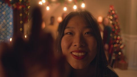 Asian woman sets timer on camera or phone. Happy multi cultural family takes group photo. They celebrating Christmas or New Year. Table with dishes and candles. Family Christmas dinner. Camera view. 库存视频