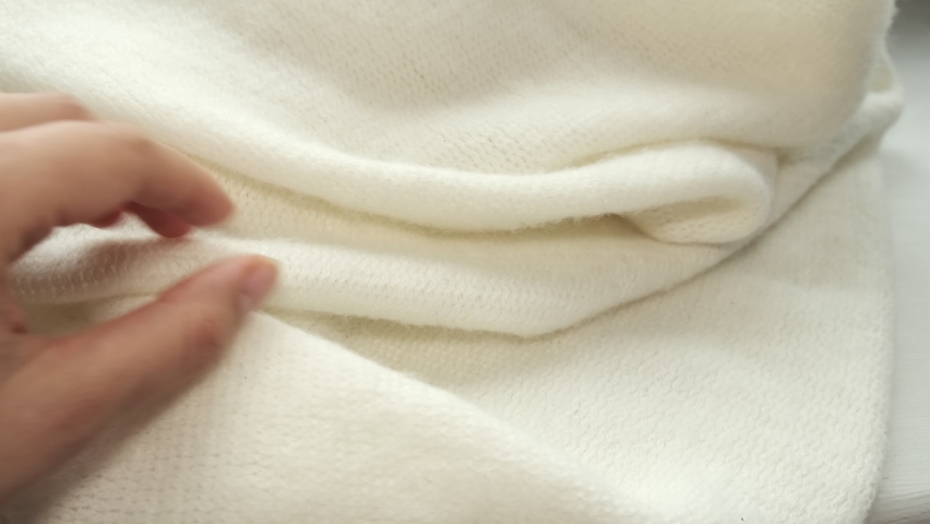 female's hand on the fabric of white plush cloth with soft nap. Clothing industry concept, slow motion. woman checking the quality of clothes, enjoys the soft pleasant texture of the fabric Royalty-Free Stock Footage #1097252857