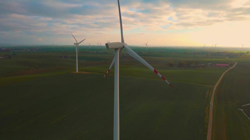 Large wind turbines with blades in field aerial view bright orange sunset blue sky with yellow rays. Clean electricity, ecological saving and alternative power source | Shutterstock HD Video #1097253405