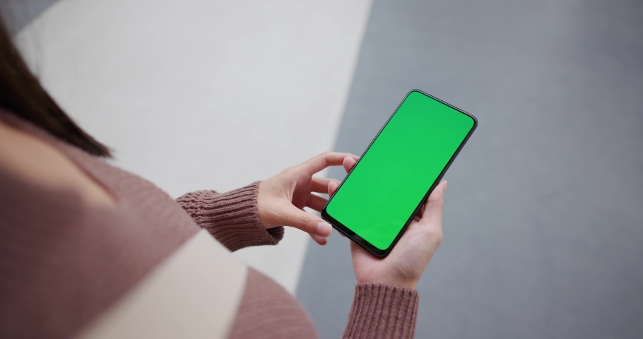 Woman hold with the green screen of mobile phone at outdoor