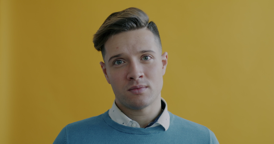 Close-up slow motion portrait of young man shaking head meaning No and looking at camera on yellow background. People and expression concept. | Shutterstock HD Video #1097254325
