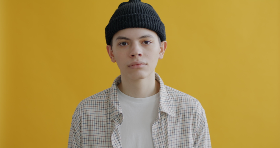 Portrait of serious teenager shaking head expressing disapproval and looking at camera against yellow color background. People and emotion concept. | Shutterstock HD Video #1097254327