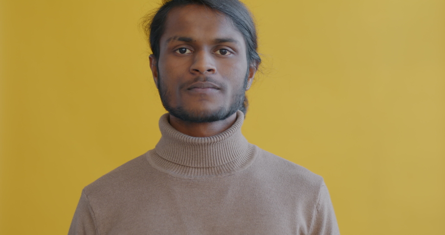Slow motion portrait of Indian guy nodding head and smiling expressing agreement on yellow color background. People and satisfaction concept. | Shutterstock HD Video #1097254349