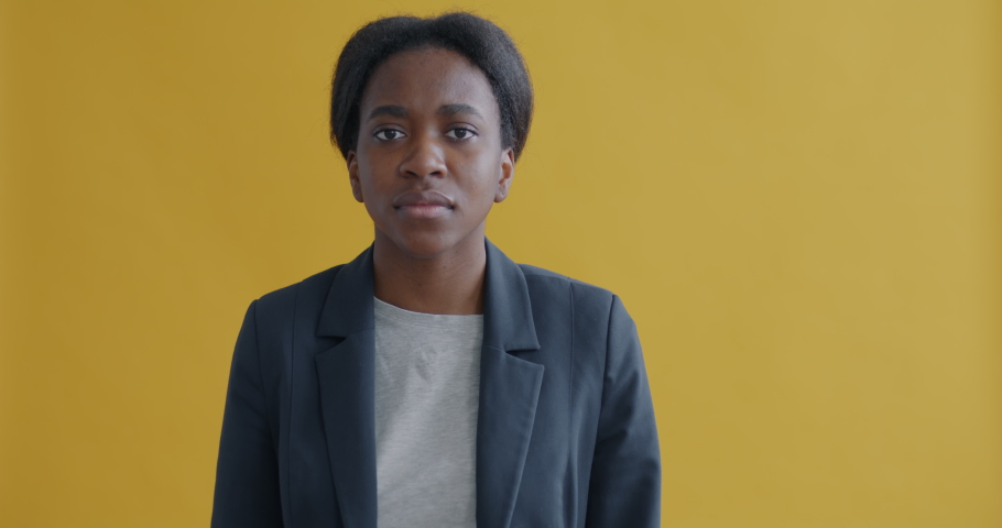 Portrait of serious African American businesswoman making shush gesture and looking at camera asking for silence on yellow background. People and expression concept. | Shutterstock HD Video #1097254351