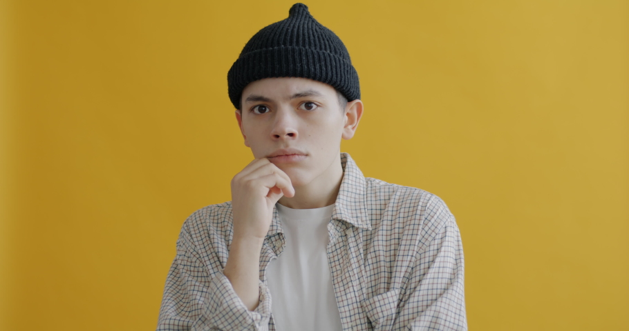 Slow motion portrait of creative teenager thinking then raising finger smiling having good idea on yellow color background. People and expression concept. | Shutterstock HD Video #1097254375