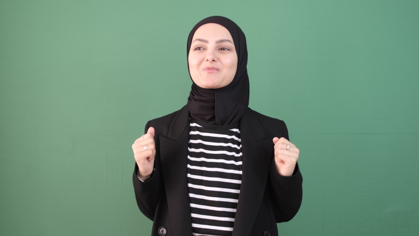 Islamic person exciting, girl feeling amazing in front of isolated green background, young person cheerful, everything is okay. | Shutterstock HD Video #1097255337