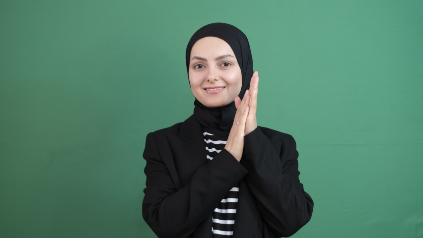 Hijab girl win sign hand, hijab girl rub hands in front of green screen, young person expression face smile, isolated green background | Shutterstock HD Video #1097255365