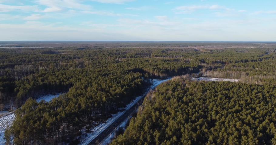 Drone flying forward over the driving road near a forest. Highway during a sunny day in winter. Travel concept. High quality 4k footage Royalty-Free Stock Footage #1097255397