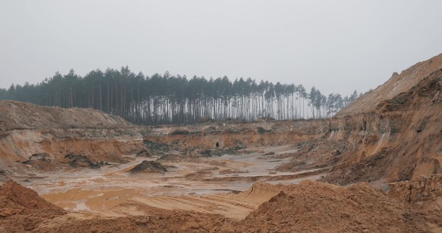 Slopes of amber quarry located near the forest with mining equipment on ledges in the forest and fog aerial view. High quality 4k footage Royalty-Free Stock Footage #1097255463