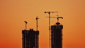Time lapse of four high-rise construction cranes on the construction of two skyscrapers. Interval shooting day and night. The concept of modern construction processes and construction technologies - Powered by Shutterstock - Get 15% off with code: PIKWIZARD15