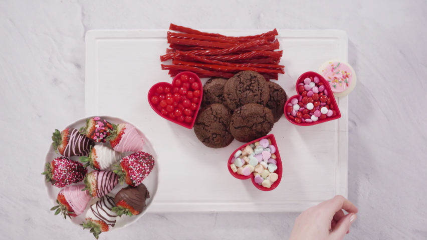 Flat lay. Step by step. Arranging cheese board with candies and cookies for Valentines Day.