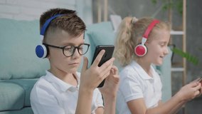 Portrait of twins girl and boy listening to music using phone and headphones, having fun at home. - Powered by Shutterstock - Get 15% off with code: PIKWIZARD15