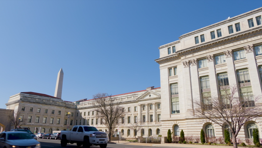 The U.S.D.A. headquarters, U.S. Department of Agriculture Jamie L. Whitten Building in Washington, D.C. The camera pans left to right from the Washington Monument as cars pass by.