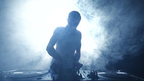 Silhouette of club dj playing vinyl music set with turntables and sound mixer. Cool young disc jockey mixing musical tracks on party