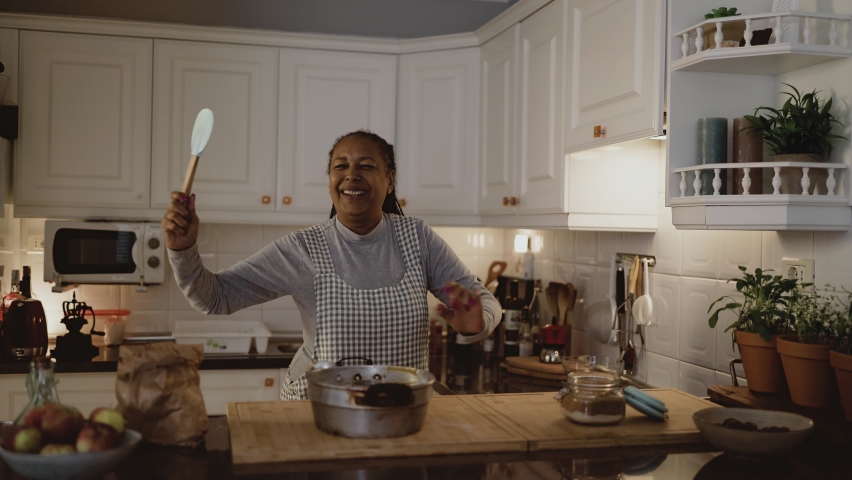 Happy senior African woman having fun dancing while preparing a homemade dessert in the kitchen Royalty-Free Stock Footage #1097266293