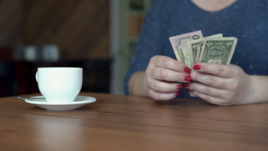 Woman hand putting US dollar banknotes on cafes table, cup of coffee on background. payment, service charge, bill checking, money tips | Shutterstock HD Video #1097266353