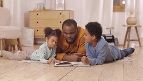 Lovely African-American family happy kids boy and girl young cheerful dad lying on floor in bright children room playing reading book. Joyful father son and daughter enjoying spending time together. - Powered by Shutterstock - Get 15% off with code: PIKWIZARD15