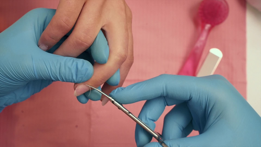 the girl does a manicure, paints her legs, removes varnish. close-up, trims cuticles, covers with base