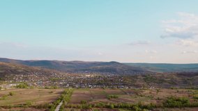 Village with green hills behind, during the golden hour. Aerial video. 4K.