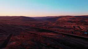 Drone footage of a landscape with arable land located on several hills at sunset. High resolution video. 4K.