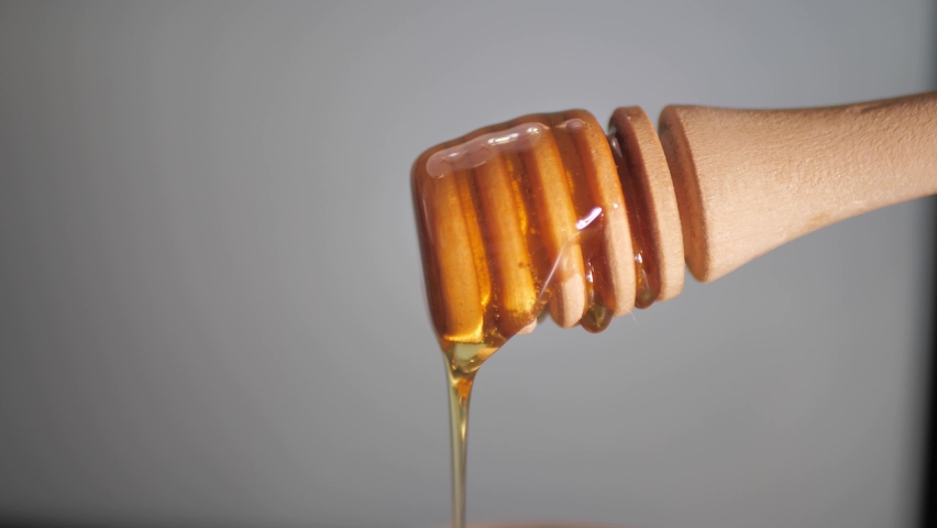 Honey dripping from a honey dipper. Healthy eating diet sustainable lifestyle concept. Close up shot with copy space. | Shutterstock HD Video #1097271087