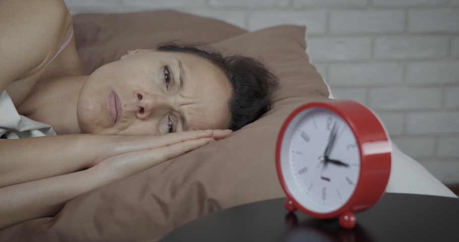 Woman trying to fall asleep. A stressed woman try to wake up because of horror dreams in the night. | Shutterstock HD Video #1097272649